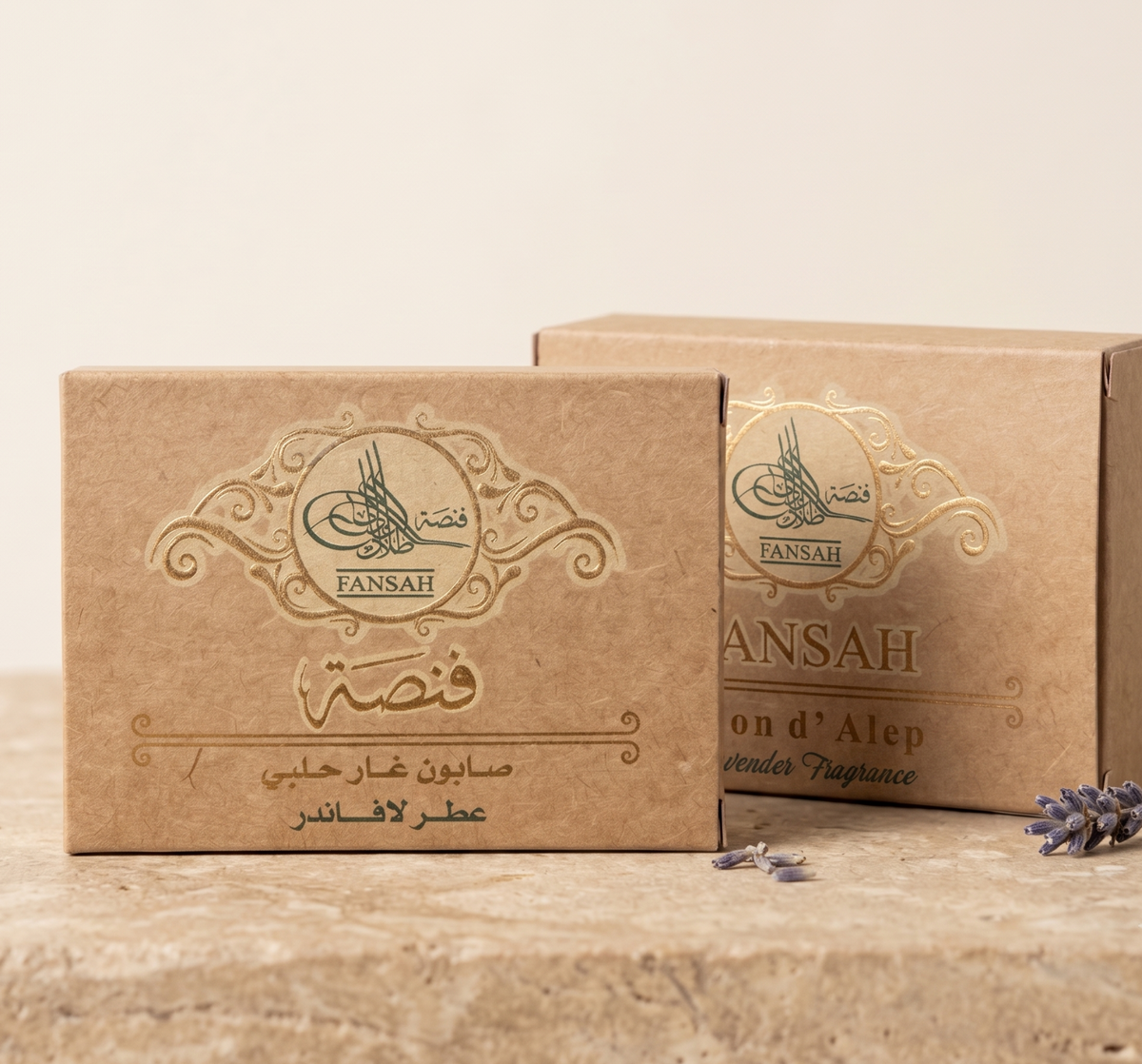 علبتان من ورق الكرافت البني لصابون الغار الحلبي برائحة اللافندر من فنصة، على سطح حجري مع خلفية بيج ناعمة