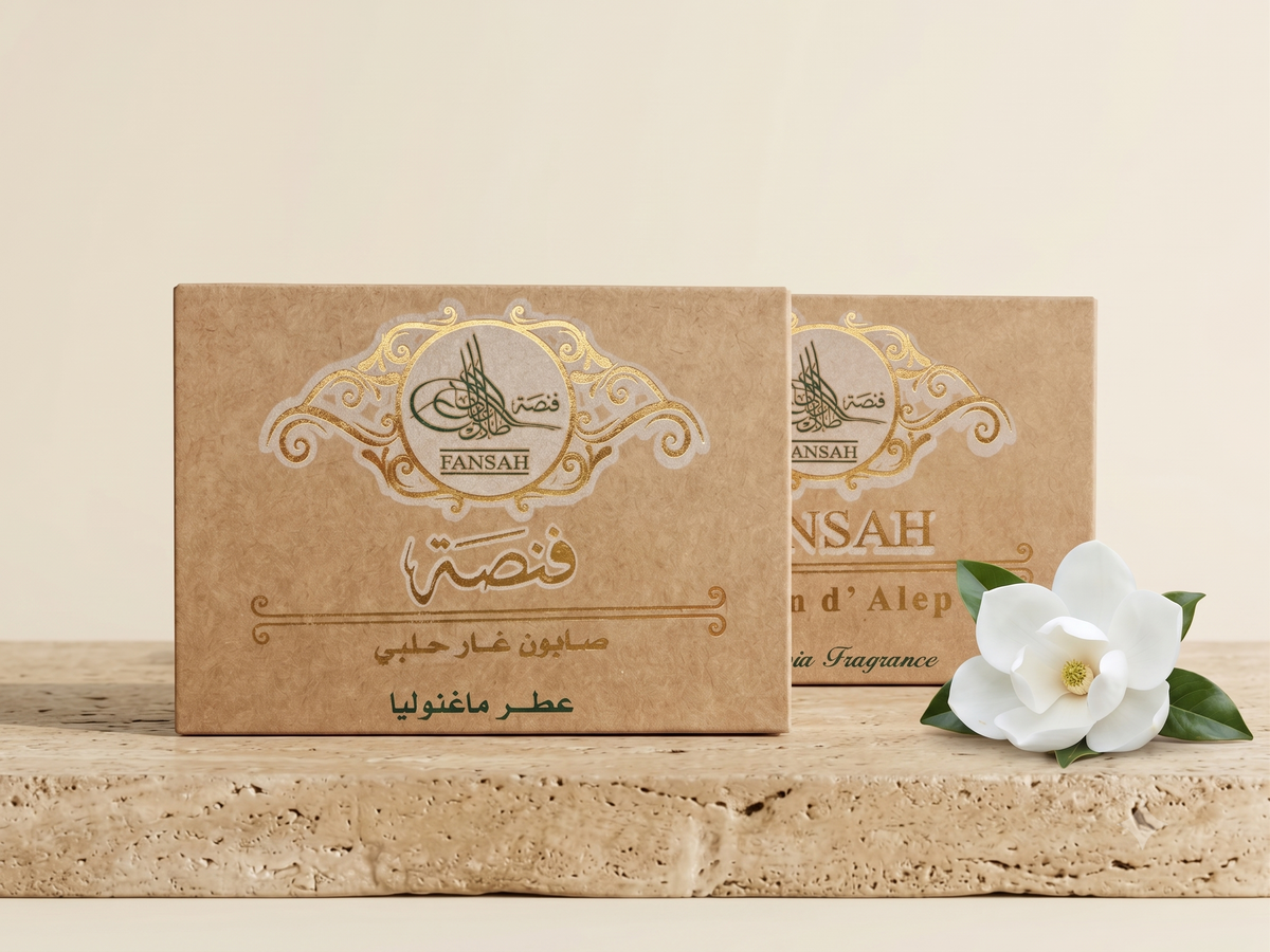 علبتا عطر مستطيلتان من فنصة بورق الكرافت الطبيعي وتفاصيل ذهبية، على سطح حجري مع زهرة بيضاء وخلفية بيج دافئة — صابون الغار الحلبي