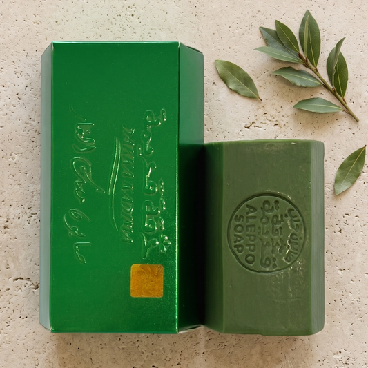 Musk Laurel Aleppo Soap by Dakka Kadima — bar shown beside its beige box on a textured stone slab, with leaves