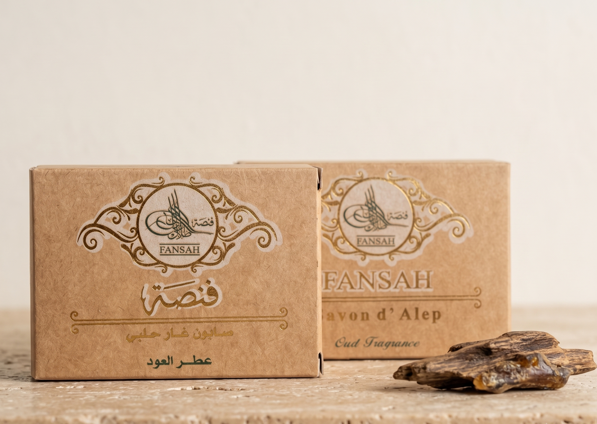 علبتان من صابون حلب بعطر الورد من فنصة بتغليف ورق الكرافت البني، على سطح حجري بجانب ثلاث بتلات ورد مجففة — صابون الغار الحلبي