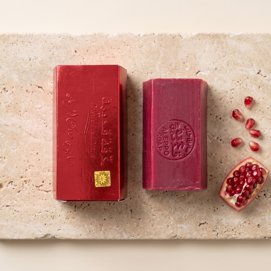 Pomegranate Musk Aleppo Soap by Dakka Kadima — two red bars displayed on a travertine slab