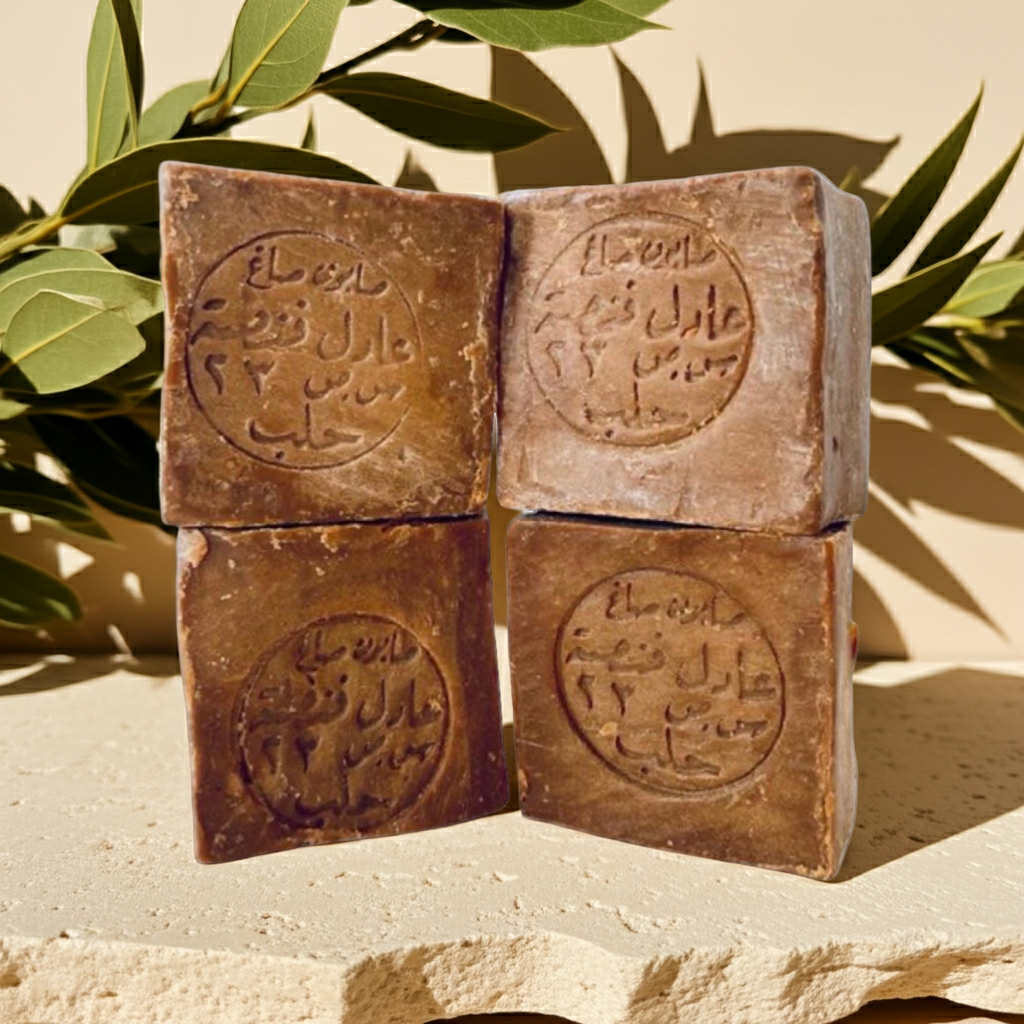 Aleppo Laurel Soap Collection by Fansa — four tan bars stacked on a stone surface, with green leaves